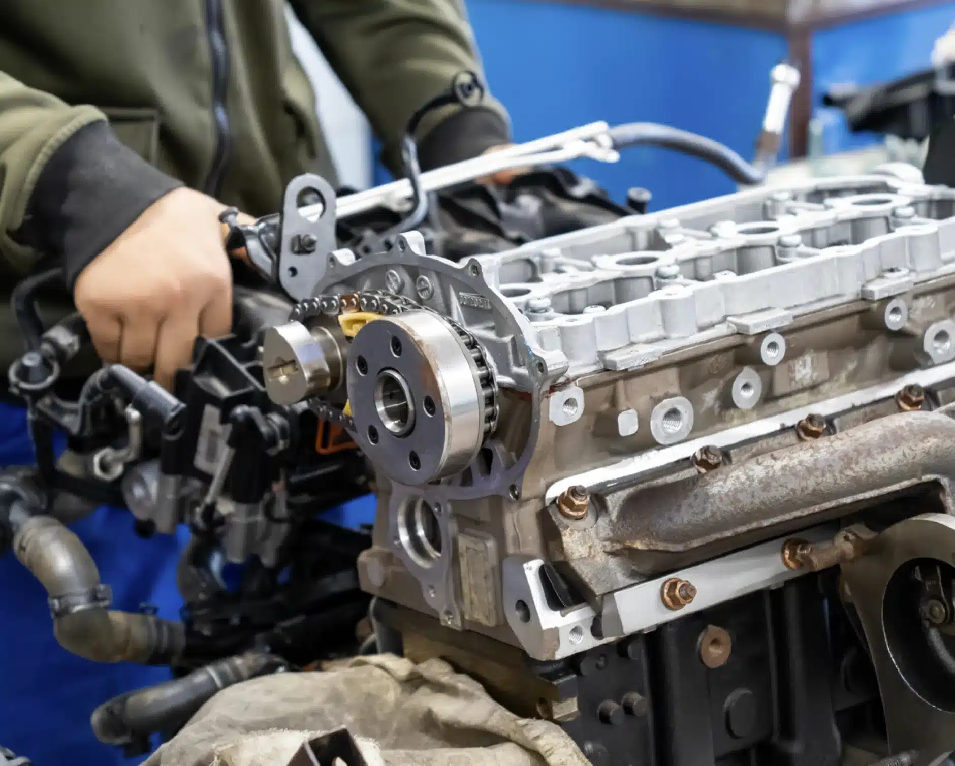 Engine repair, auto repair in New Braunfels, TX by Clark's Auto Service. A person working on a partially assembled car engine, adjusting components with tools in a workshop setting.